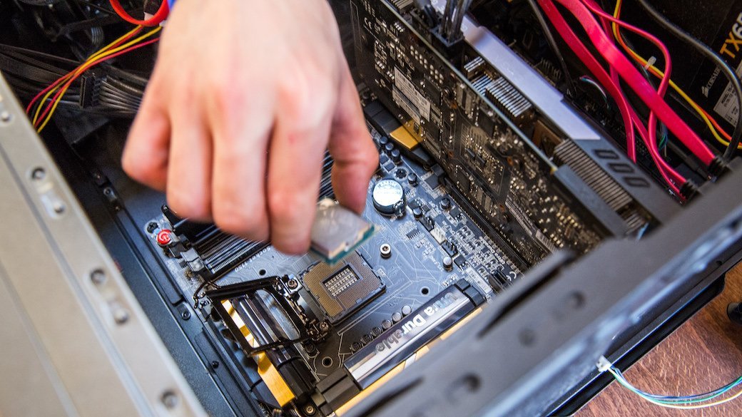 A hand reaches into an open computer case to make adjustments.