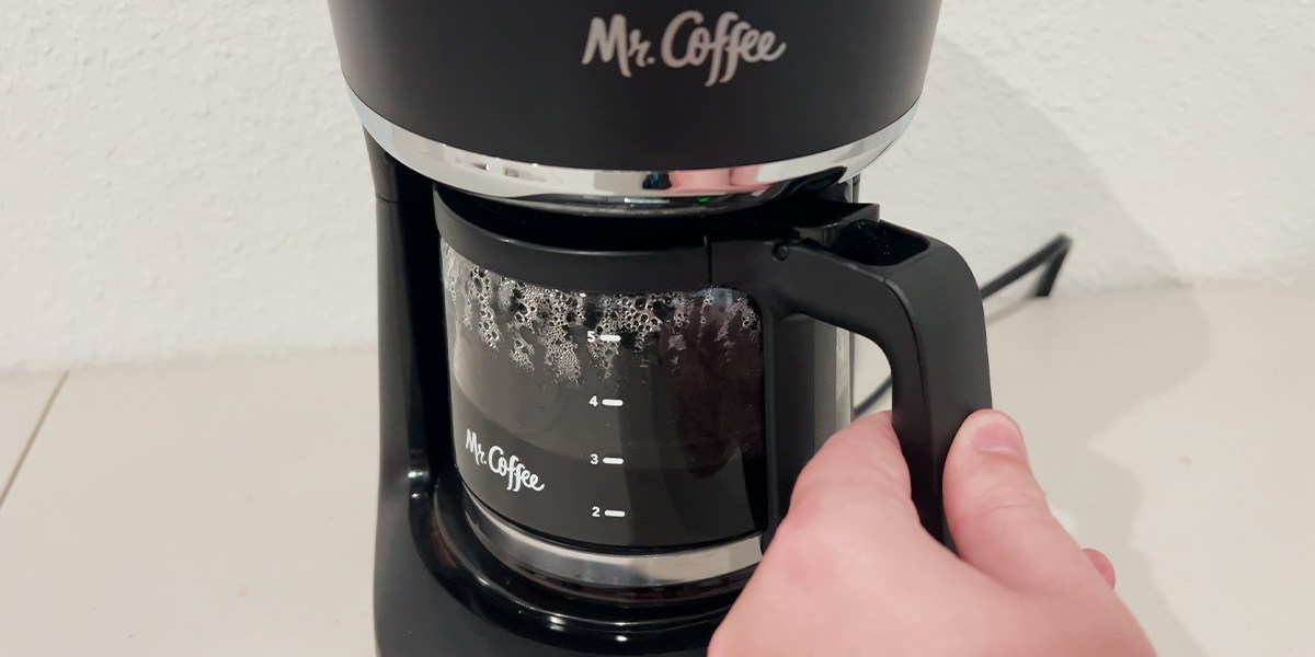 Closeup of Mr. Coffee Programmable Mini Brew with hand on carafe handle Closeup of Mr. Coffee Programmable Mini Brew with hand on carafe handle