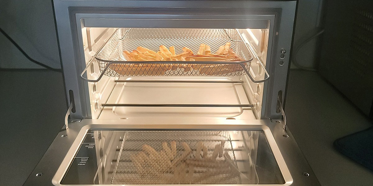 Cosori Smart Air Fryer Toaster Oven with fries in cooking basket Cosori Smart Air Fryer Toaster Oven with fries in cooking basket