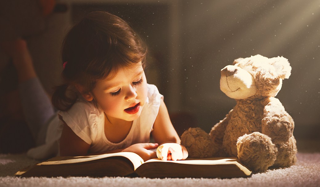 Child reading to toy bear