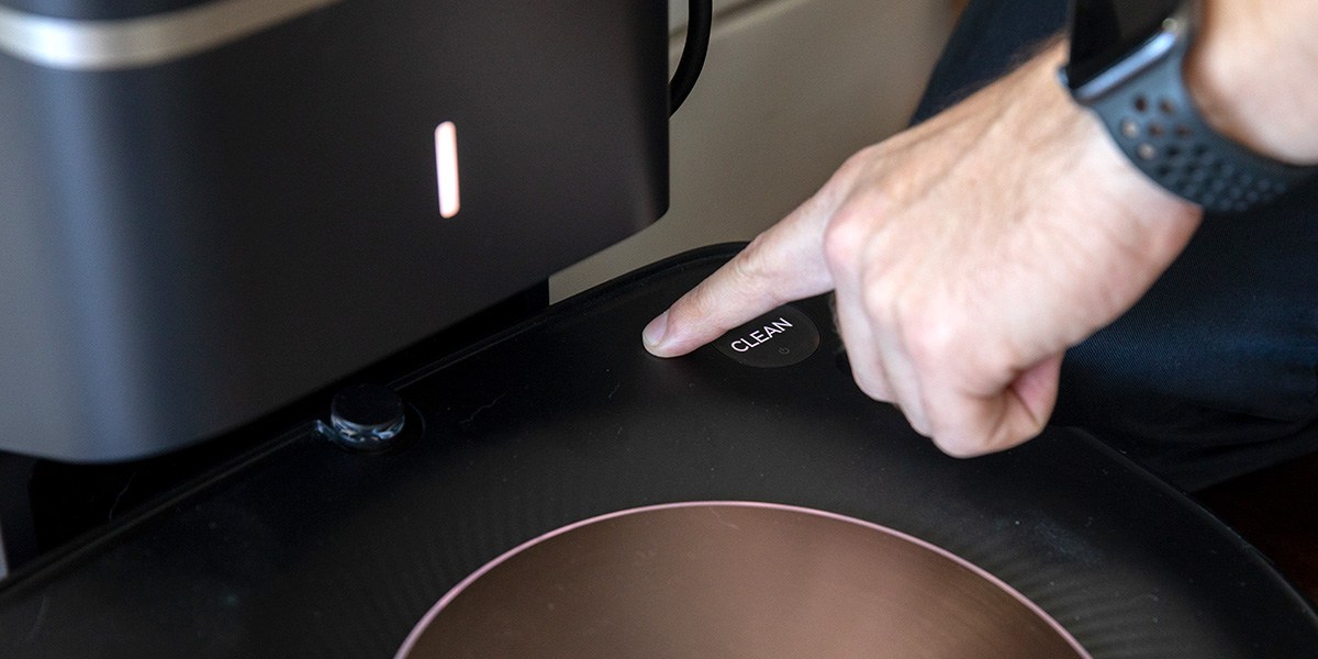 Person pressing button on Roomba